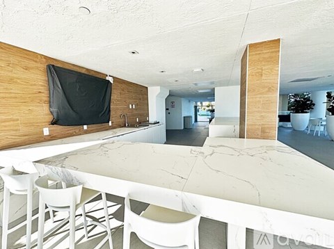 A modern kitchen with a long white table and chairs.