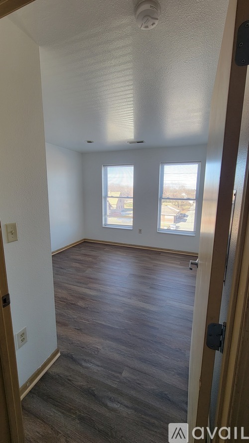 A room with wooden floors and a window overlooking a parking lot.