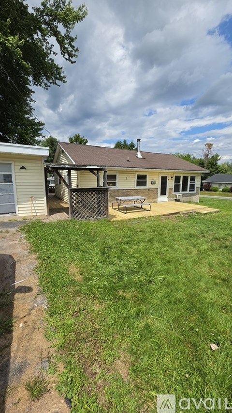 A house with a patio and a tree in front.