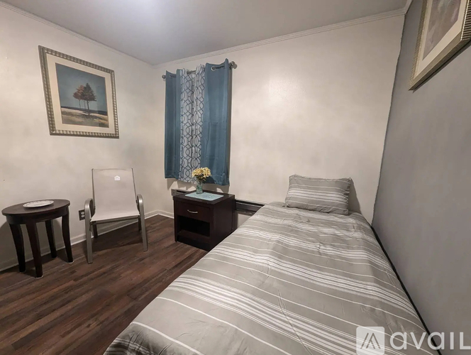 A bedroom with a bed, chair, and table.