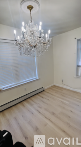 A room with a chandelier and wooden flooring.