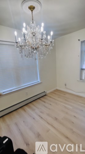 A room with a chandelier and wooden flooring.