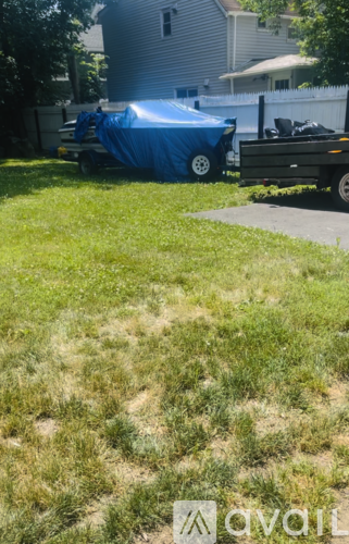 A blue tarp is covering a white object in a yard.
