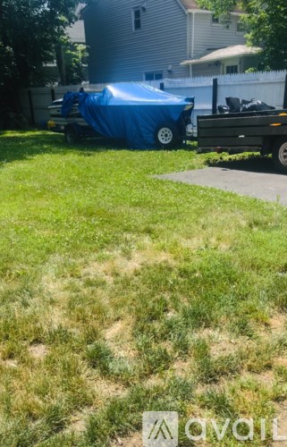 A blue tarp is covering a white object in a yard.