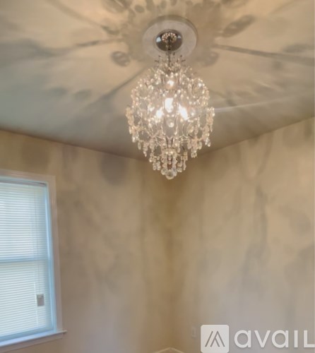A chandelier hangs from a ceiling in a room with a window.
