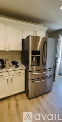 A kitchen with a stainless steel refrigerator and white cabinets.