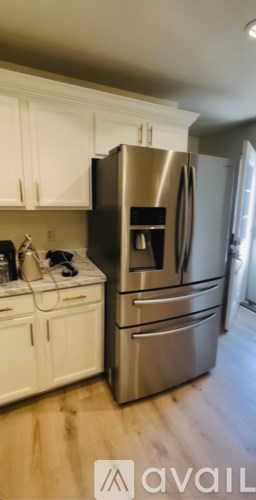A kitchen with a stainless steel refrigerator and white cabinets.