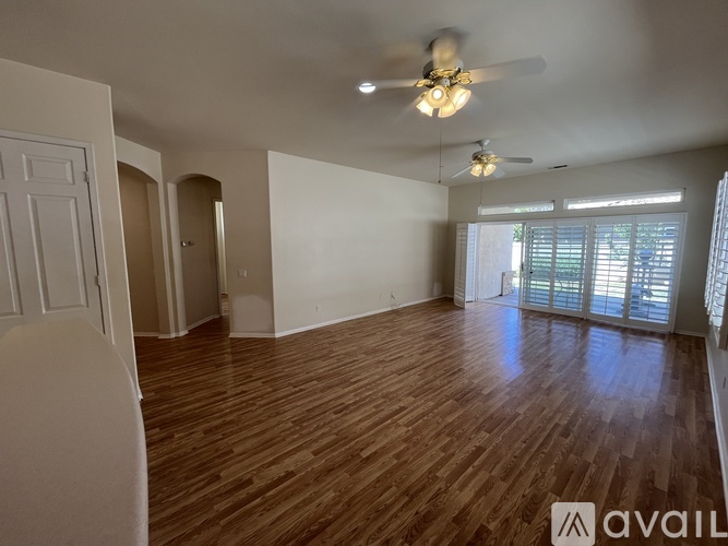 A spacious room with wooden flooring and a ceiling fan.