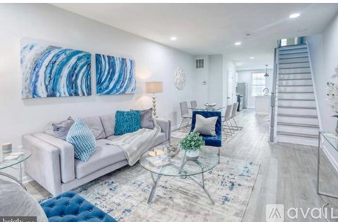 A living room with a white couch, a glass coffee table, and a blue rug.
