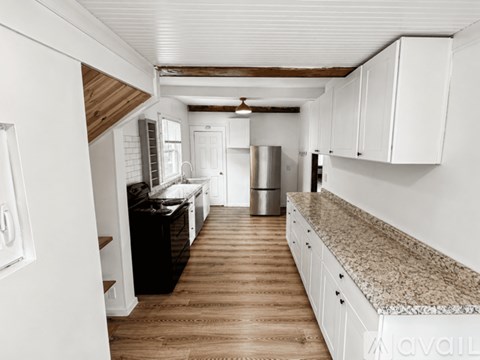 A kitchen with white cabinets and a wooden floor.