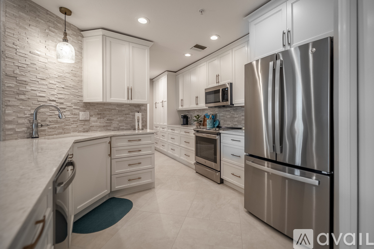 A modern kitchen with a stainless steel refrigerator and white cabinets.