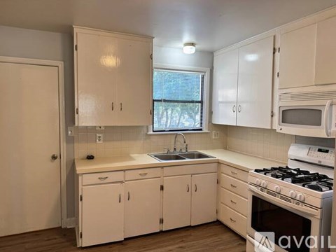 A kitchen with white cabinets and a window.