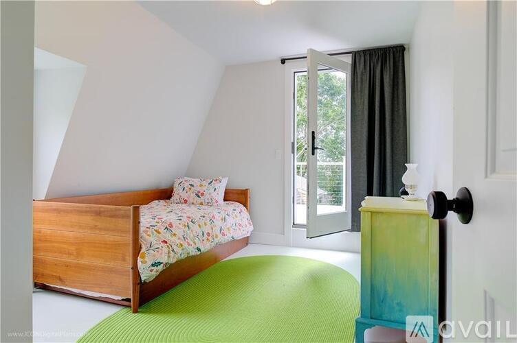 A bedroom with a bed, a green mattress, a wooden nightstand and a door leading outside.