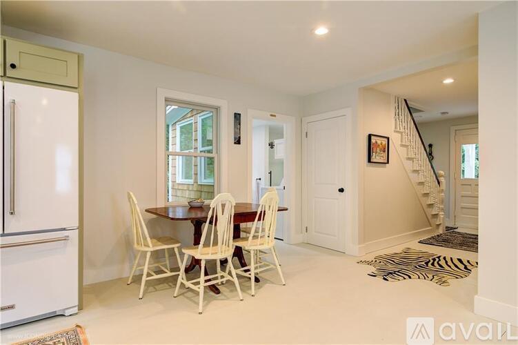 A kitchen with a white fridge, a dining table with chairs and a staircase.