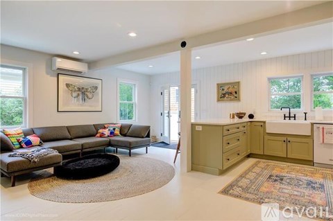 A living room with a grey sofa and a rug.