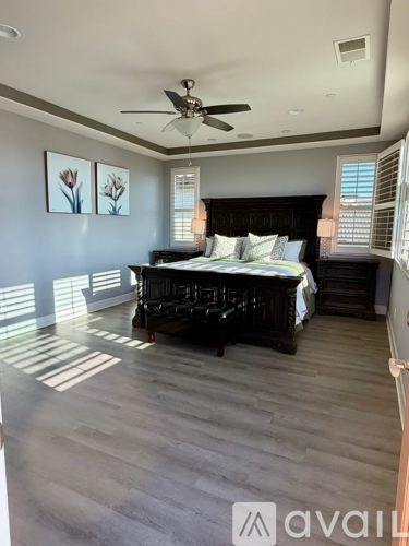 A bedroom with a large bed and a ceiling fan.