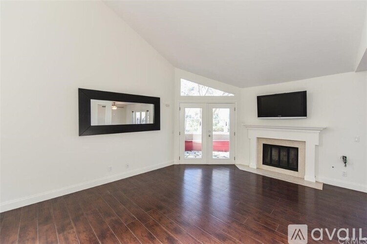 A living room with a fireplace and a flat screen TV mounted on the wall.