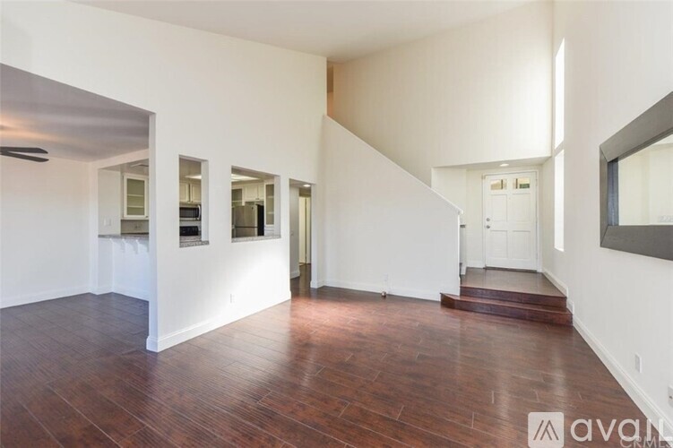 A spacious room with wooden floors and white walls.