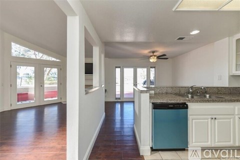 A kitchen with a blue dishwasher and wooden floors.