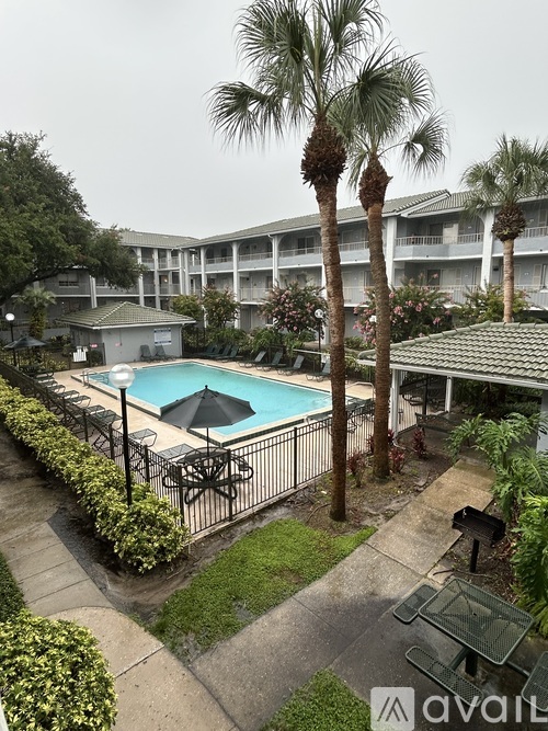 A pool surrounded by palm trees and a building in the background.