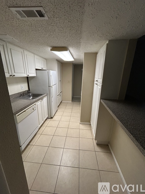 A kitchen with white cabinets and a black counter.