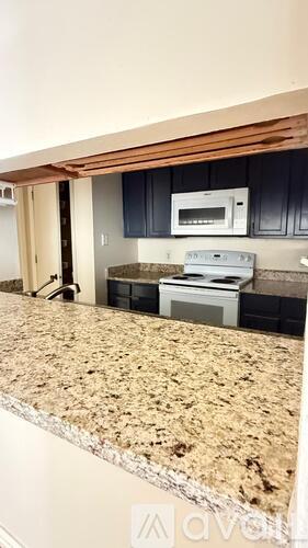A kitchen with granite countertops and black cabinets.