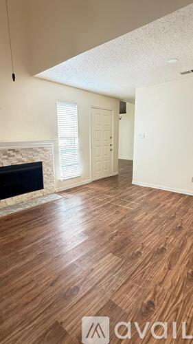 A room with wooden flooring and a fireplace.