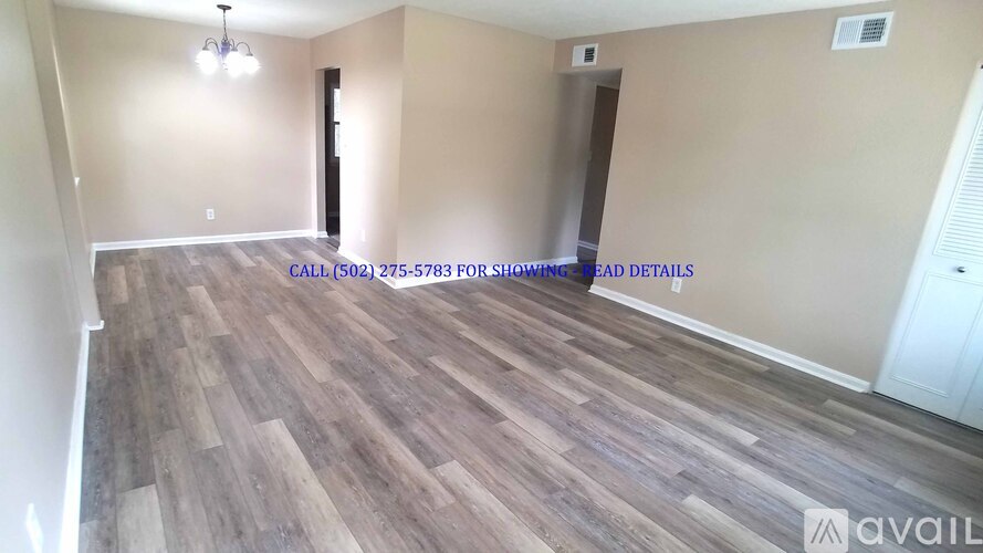 A room with wooden flooring and a door on the right side.