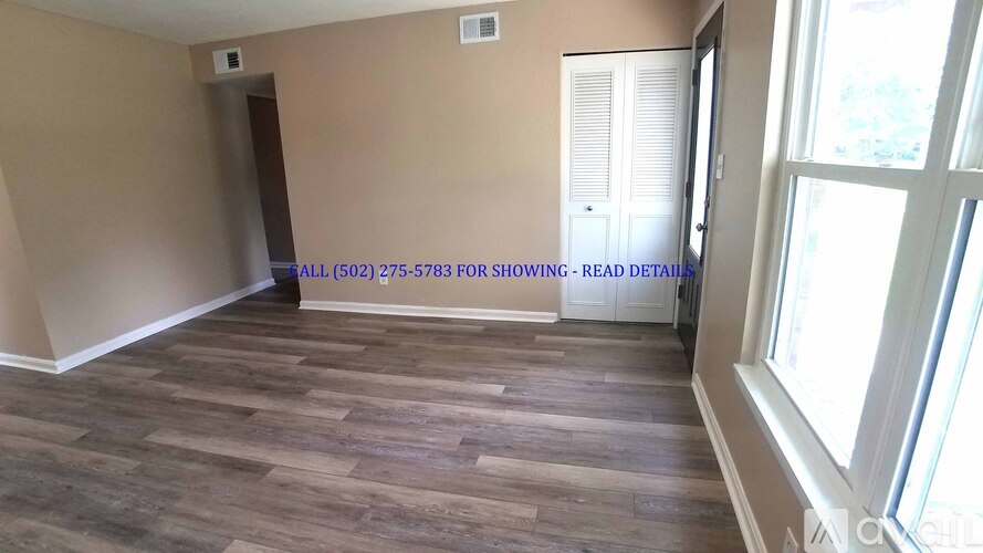 A room with wood flooring and a window on the right side.