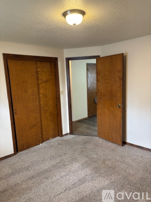 A room with a carpeted floor and two wooden doors.