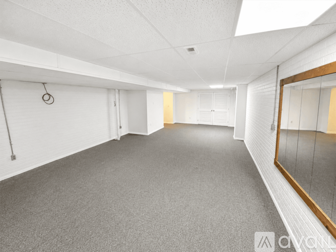 A spacious room with a grey carpet and white walls.