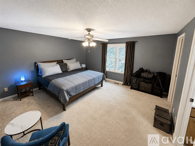 A bedroom with a bed, chair, and window.