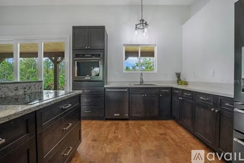 A kitchen with dark wood cabinets and a granite countertop.