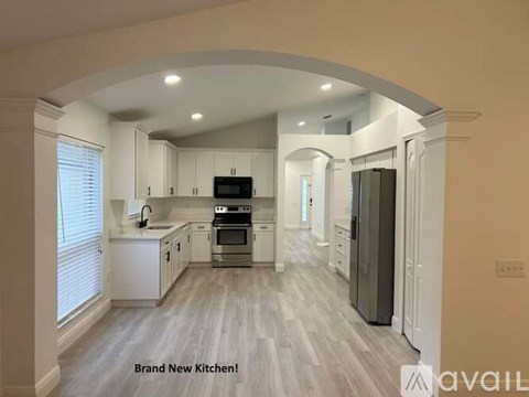 A brand new kitchen with white cabinets and a grey floor.
