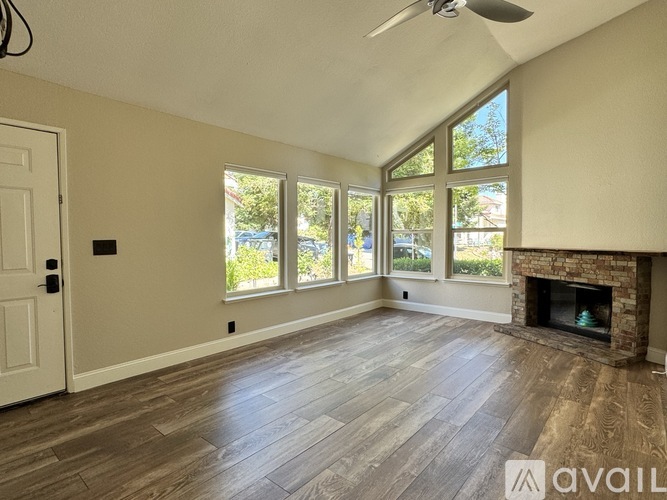 A spacious room with a fireplace and a ceiling fan.