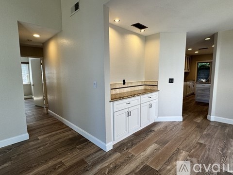 A kitchen with white cabinets and a wooden floor.