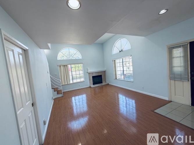 A spacious living room with wooden floors and white walls.