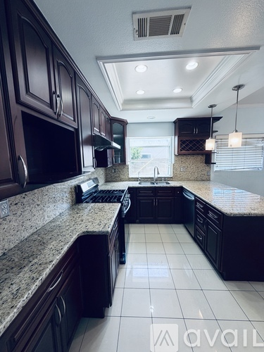 A kitchen with dark brown cabinets and granite countertops.