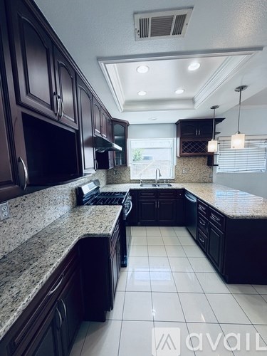 A kitchen with dark brown cabinets and granite countertops.