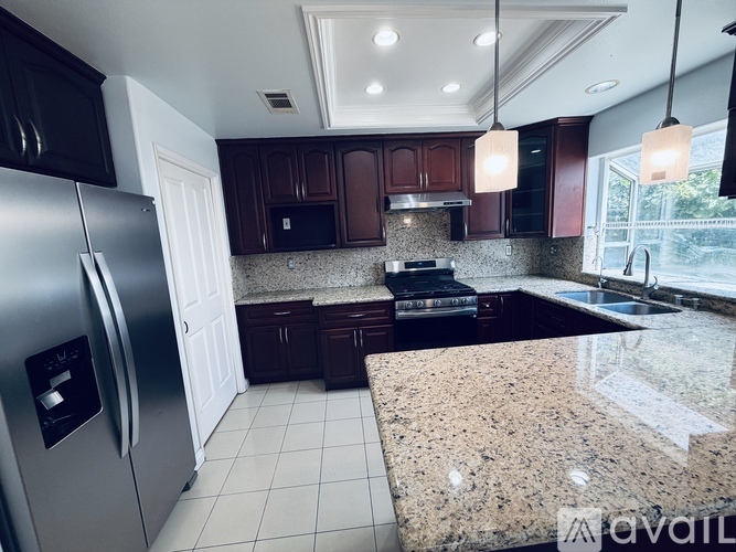A kitchen with granite countertops and a refrigerator.