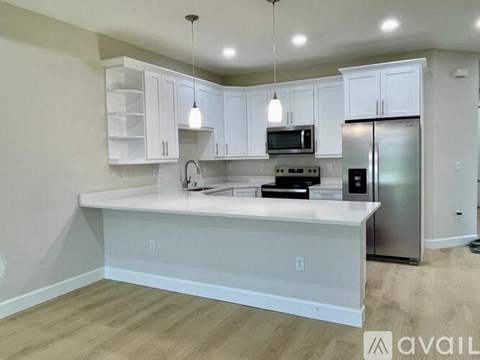 A kitchen with white cabinets and a stainless steel refrigerator.