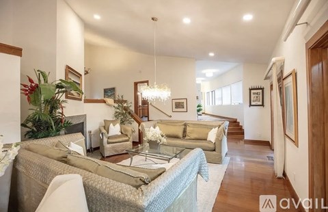 A well-lit, spacious living room with a staircase and a large bed.