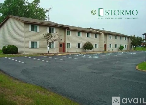A parking lot in front of a building with the sign "STORMO REAL ESTATE AND PROPERTY MANAGEMENT".