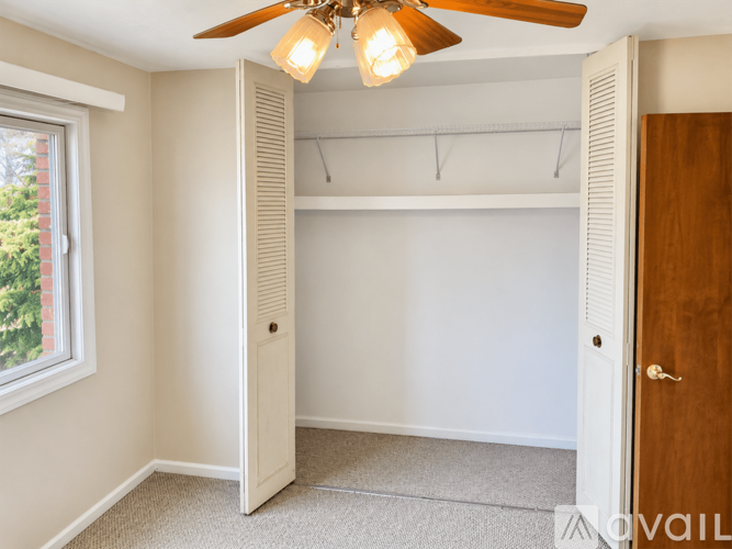 A bedroom with a ceiling fan and a window.