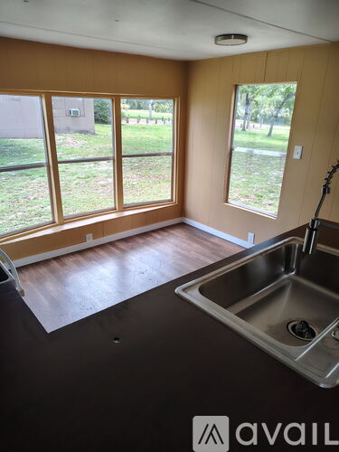A kitchen with a sink and a window overlooking a lawn.