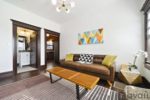A living room with a brown couch and a colorful painting on the wall.