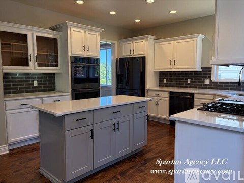 A kitchen with white cabinets and a black refrigerator.