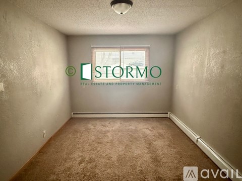 A room with a carpeted floor and a window with a view of a building outside.