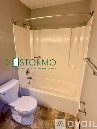 A white toilet sits next to a bathtub in a bathroom.