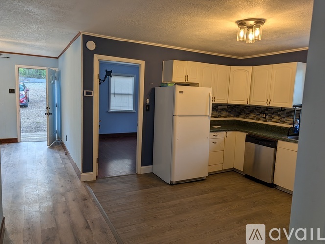 A kitchen with a white refrigerator and wooden floors.